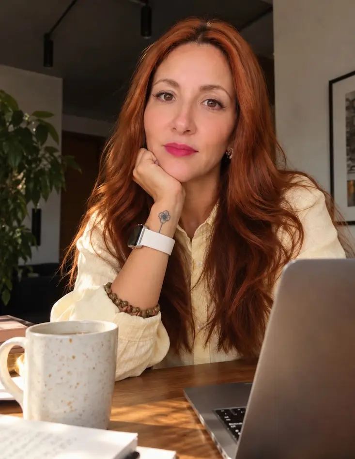 Rose, curadora da A.feto, à mesa de trabalho com uma caneca e o notebook